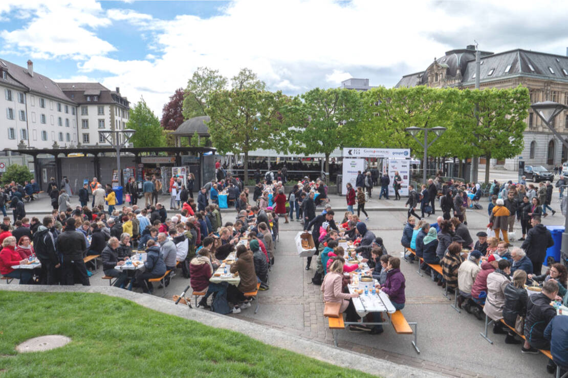 Photo de la place Python à Fribourg où plusieurs personnes mangent une fondue à l'occasion du 125ème anniversaire de GastroFribourg