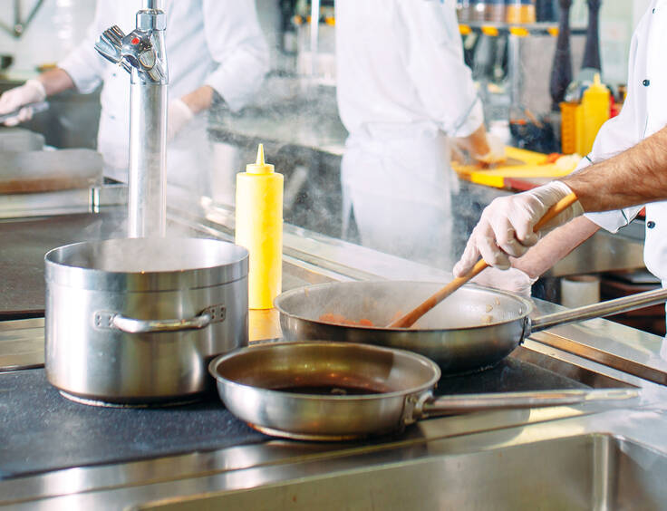 Plusieurs casseroles sur une plaque dans la cuisine d'un restaurant